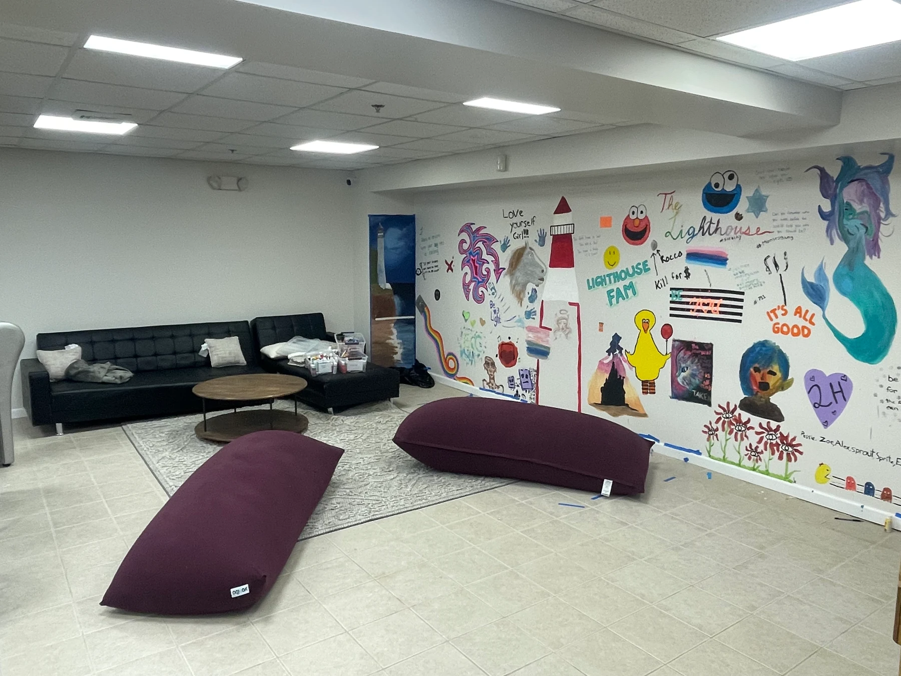 Inside the Lighthouse lounge, with comfortable seating and a colorful community art wall
